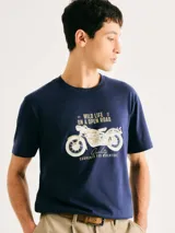 Camiseta blanca de algodón con cuello redondo y mangas cortas. Estampa rectangular con borde negro que contiene la frase "NATURAL ATMOSPHERE" en letras mayúsculas y una imagen de montañas y mar.