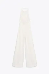 Mono largo blanco de cuello halter con botones y espalda descubierta. Pierna ancha y cierre trasero con cremallera oculta.