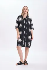 Vestido corto camisero de viscosa con estampado abstracto en blanco sobre fondo negro, de mangas cortas y corte holgado.