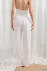 Pantalón de lino blanco, de corte ancho y tiro alto, con cintura elastizada y cordón ajustable.
