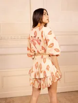 Top corto color crema con estampado de cachemir en tonos naranja y rosa, escote elástico con volantes, mangas cortas abullonadas y corte crop.