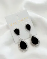 Par de caravanas colgantes plateadas con incrustaciones de strass y dos gemas negras en forma de lágrima.