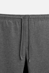 Pantalón negro de corte cropped, con cintura elástica ajustable con cordón, bolsillos laterales y traseros de vivo. El bajo tiene terminación con vuelta.