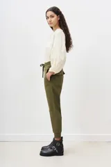 Pantalón tipo babucha color verde militar, confeccionado en gabardina elastizada, con ajuste en tobillos y cintura regulable con cordón a tono. Cuenta con bolsillos diagonales en el frente y bolsillos con solapa y botón en la parte trasera.