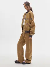 Pantalón de denim color marrón claro, de tiro alto, corte amplio y pinzas en la cintura.