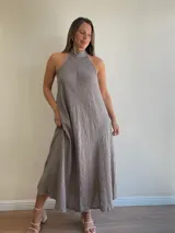 Vestido largo confeccionado en 100% lino, con cuello halter y silueta fluida en color beige.