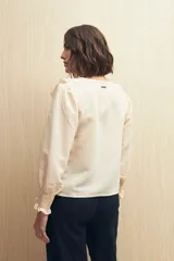 Camisa blanca a rayas verticales, con escote en V, mangas 3/4 con puños elastizados y volados.