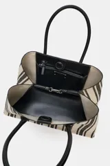 Bolso tipo shopper de mano de lona color crudo con rayas verticales negras y asas de cuero sintético negro. Tiene tira interior con cierre de mosquetón metálico, bolsillo interior con cierre de cremallera y cierre imantado.