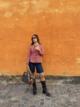 Blusa celeste y blanca a rayas verticales con cuello cuadrado, mangas largas con frunce en los hombros y corte peplum. Cierre frontal con botones. 