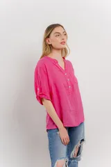 Camisa azul de lino con escote en V abotonado, bolsillo frontal y mangas 3/4 con trabilla.
