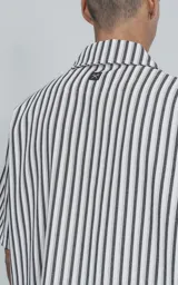 Camisa de manga corta con cuello abierto y calce oversize, confeccionada en sarga liviana con estampado de rayas verticales en negro y blanco.