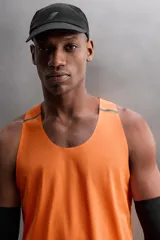 Camiseta deportiva sin mangas color beige, confeccionada en tejido técnico ligero y elástico con estructura perforada. Tiene cuello redondo amplio, sisas con acabados termofijados, bajo con aberturas laterales y logo estampado.