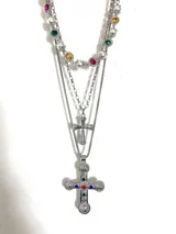 Set de tres collares plateados de acero quirúrgico. El primero es de perlas con piedras de colores, el segundo es una cadena con una cruz pequeña y el tercero es una cadena con una cruz grande con incrustaciones de strass y piedras de colores.