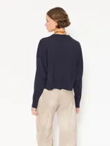 Sweater tejido suave y flojo, color crudo, con cuello redondo y mangas largas.