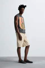 Camiseta sin mangas gris oscuro de corte holgado, con cuello redondo y estampado frontal de un hombre con sombrero y camisa floreada. Diseño de la colaboración especial Zara x Otis Kwame Kye Quaicoe.
