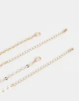 Collar corto dorado con doble cadena, una de eslabones grandes y otra de eslabones pequeños. Dije redondo con diseño de moño rosa y strass.