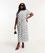 Vestido midi blanco con lunares negros, de corte suelto, cuello redondo y mangas cortas.