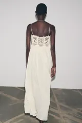 Vestido largo color crudo, de algodón, con tirantes finos y escote recto. Presenta detalle de crochet en la parte superior.