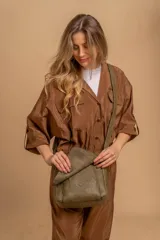 Bandolera de hombro color gris claro, con solapa frontal y correa ajustable. Presenta un diseño simple y práctico, ideal para uso diario.