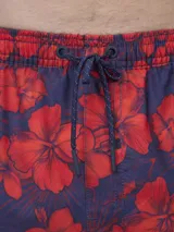 Short de baño verde con estampado de margaritas blancas y cordón ajustable naranja.