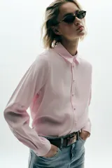 Camisa rosa de cuello solapa y manga larga. Tejido suave. Cierre frontal con botones a tono.