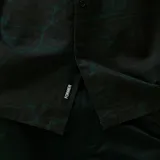 Camisa de manga corta, color negro, con cuello camisero y estampado abstracto en tonos verde esmeralda.