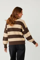 Sweater de tejido grueso, holgado, con cuello redondo y mangas largas. Presenta un diseño de rayas horizontales anchas en color rosa claro y marrón oscuro.