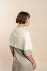 Chal asimétrico de lana color gris claro, con cortes en los hombros y doble ojal de fieltro para mantener el cruce. Terminación pespunteada y al corte.