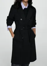 Trench coat negro con cuello de solapa, doble botonadura, trabillas en los puños, cinturón ajustable y abertura posterior en el bajo.