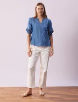 Blusa de lyocell color celeste, con cuello a la base, escote en V y botones. Delantera con bolsillo. Manga corta con terminación en punto smock.
