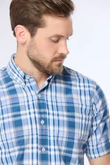 Camisa de manga corta con cuello abotonado y estampado a cuadros en tonos de azul y blanco. Hecha en Uruguay.