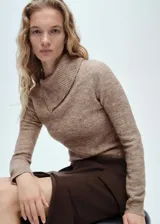 Sweater color beige de tejido de punto, con cuello solapa alto y mangas largas.