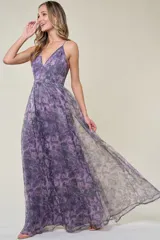 Vestido largo de fiesta con estampado floral en tonos grises, negros y rosados. Tiene escote en V, tirantes finos y falda amplia de organza.