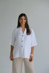 Camisa blanca de lino con cuello mao, manga corta y cierre frontal con botones.