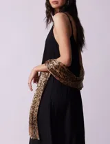 Pashmina de poliéster con estampado animal print y lurex dorado. Terminación con flecos.