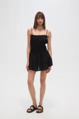 Vestido corto negro de algodón con breteles finos, escote recto, corte holgado, cintura elastizada y volados en el ruedo.