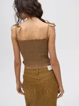 Top corto negro con textura fruncida, tirantes finos con lazos ajustables y corte crop.