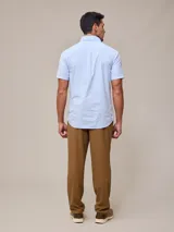 Camisa de algodón blanca de manga corta, con cuello abotonado y botones frontales.