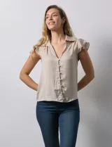 Camisa color beige de satén, con cuello con solapa y escote en V. Tiene una apertura central con botones y sisas con volados.