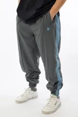 Pantalón de jogging gris con forro interno de red, bolsillos laterales con cierre, cierres en los tobillos y logo bordado.