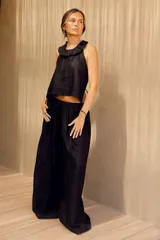 Pantalón negro de corte amplio con pinzas en la cintura, regulable con elástico y tiras.