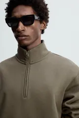 Sudadera negra de algodón con cuello alto y cierre de cremallera. Corte relaxed fit, manga larga y terminaciones en rib.