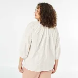 Blusa blanca con bordado calado, escote con lazo y mangas 3/4 abullonadas.