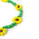 Pulsera bijou dorada con mostacillas en tonos verdes y amarillos, con detalles de flores.