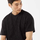 Camiseta negra de manga corta con cuello redondo y diseño jacquard de hojas.