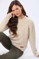 Buzo tejido de abrigo color beige, con cuello redondo y mangas largas. Presenta un delicado diseño bordado en el frente con pequeños motivos en tonos pastel.