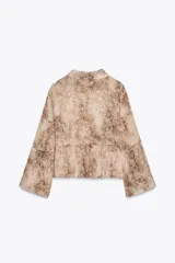 Camisa con estampado animal print en tonos beige y marrón, con cuello solapa y escote pico. Manga larga con capas en mismo tejido y bajo acabado en volantes. Cierre frontal con botones y lazada.