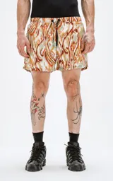 Short de baño de calce regular con estampado abstracto en tonos verdes, naranjas y marrones. Posee cintura elástica con cordón de ajuste negro y un pequeño logo negro en el lateral inferior derecho.