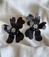 Par de aros con forma de flor color negro con glitter y centro con strass.