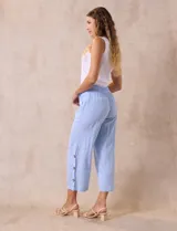 Pantalón blanco de algodón con pretina elastizada, bolsillos inclinados y ruedo lateral con tajo y botones.